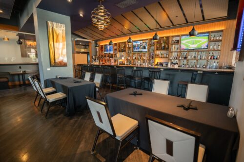 The interior of the Eclipse Restaurant, showing a few empty tables and a bar with a glow of ambient lighting