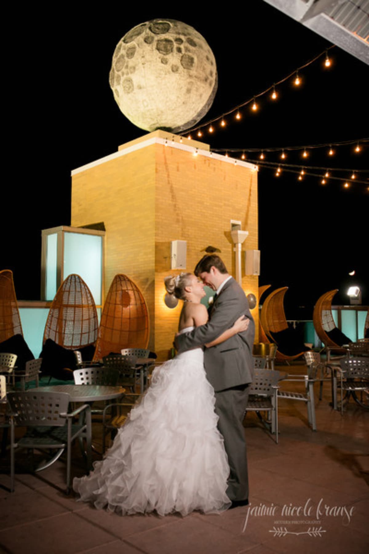 a married couple hold one another below the rooftop moon statue A married couple hold one another below the rooftop moon statue.