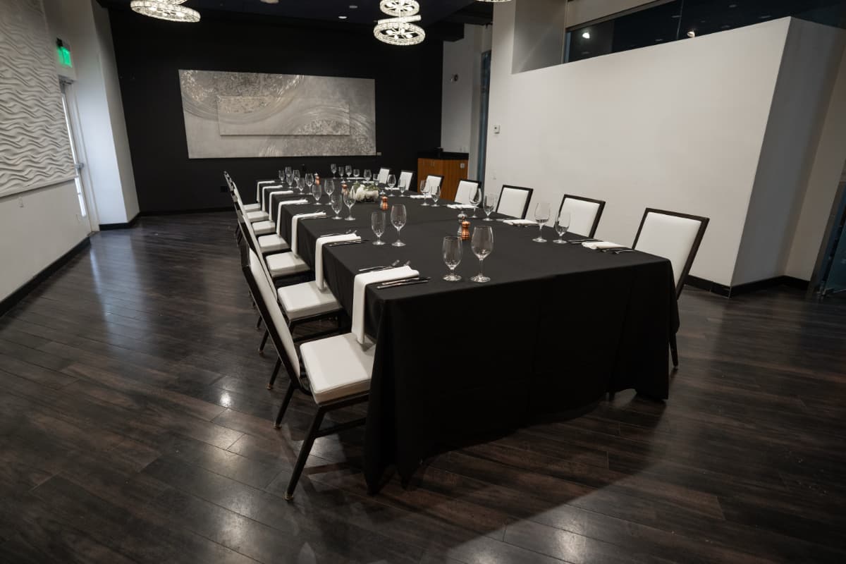 gemini room A meeting room with a large table with black table cloth. It has 14 place settings and chairs around it.