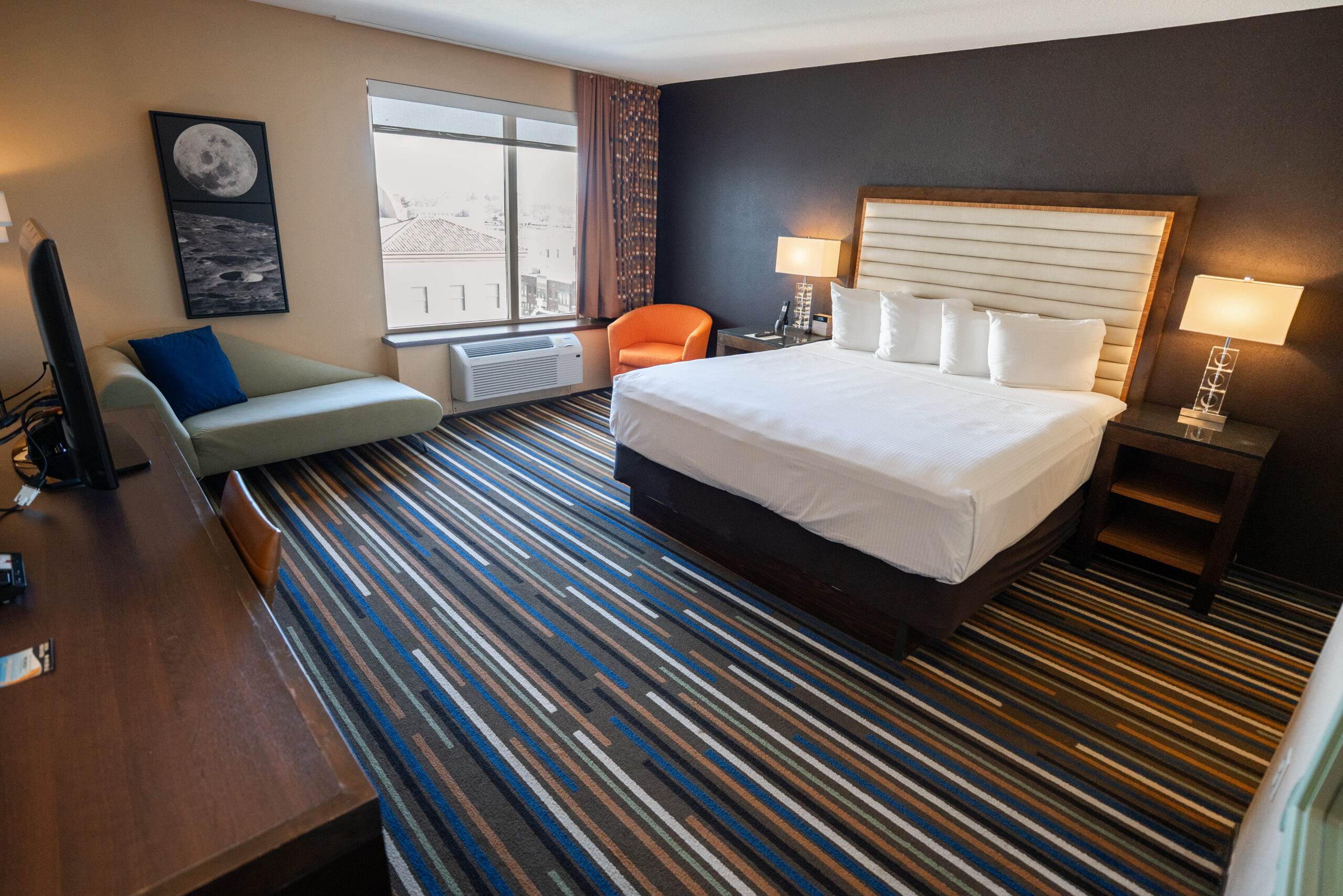 A bottle of champagne chills in an ice container, and two empty champagne flutes sit next to it. The rest of the hotel room is in the background.